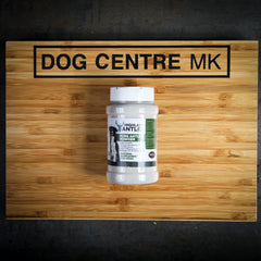 A 500ml bottle of pure deer antler powder for dogs, displayed on a wooden surface with a 'Dog Centre MK' logo in the background.