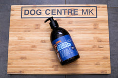 A 500ml bottle of Nova Scottish Salmon Oil for dogs, placed on a wooden surface with the brand name 'DOG CENTRE MK' visible in the background.