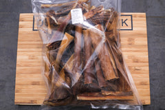 A plastic-wrapped 1kg package of dried beef skin, placed on a wooden board with dog centre mk branding
