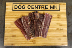 flat strips of dried meat on dog centre mk branded wooden board