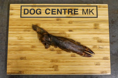 A piece of wild boar meat on a wooden board with the text 'DOG CENTRE MK' carved on top.