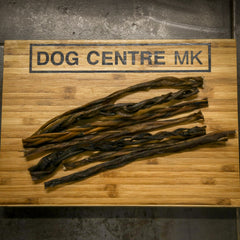 Dried dog treats on a wooden board with 'DOG CENTRE MK' branding.