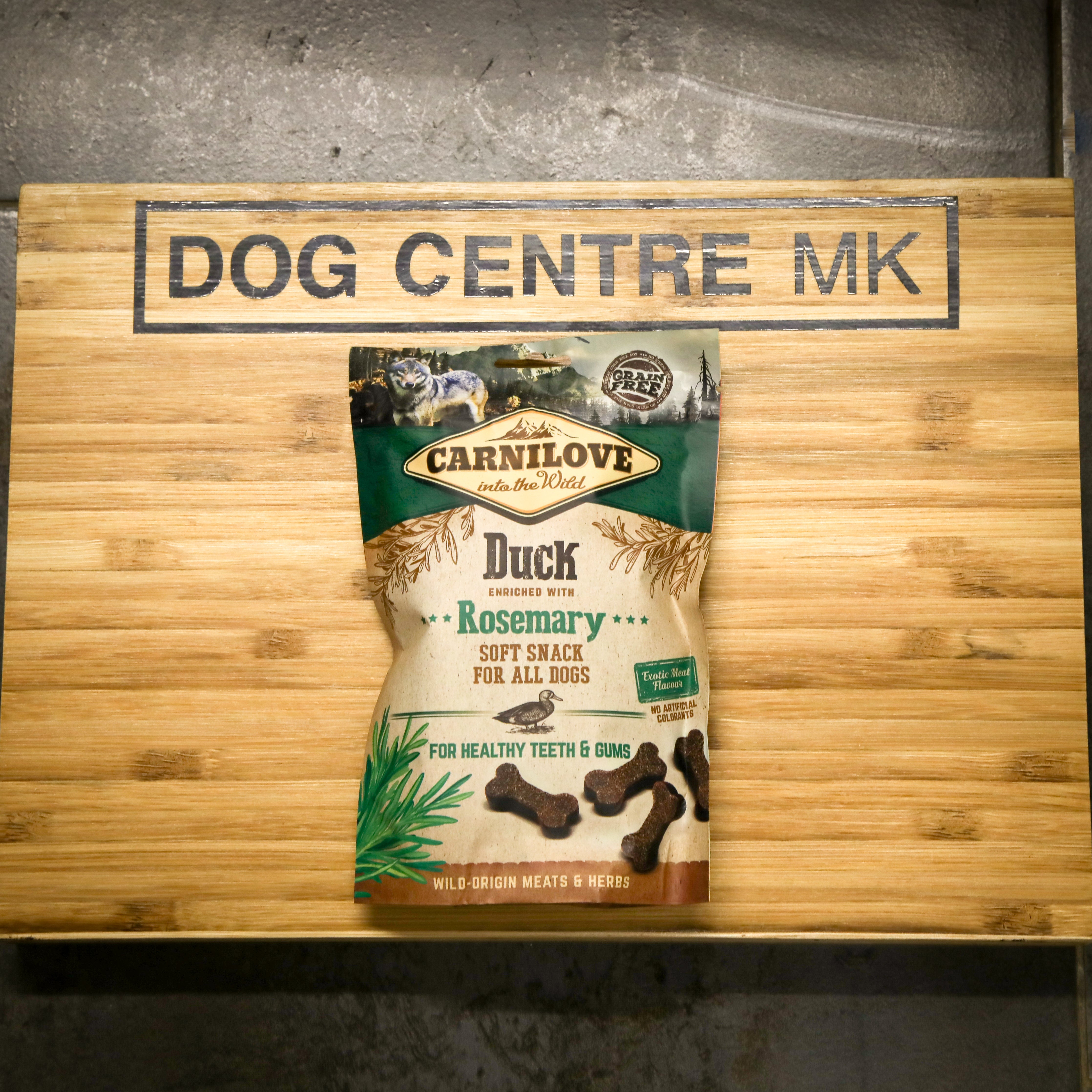 CarniLove Duck Rosemary soft snack for dogs on a wooden board with 'Dog Centre MK' sign.