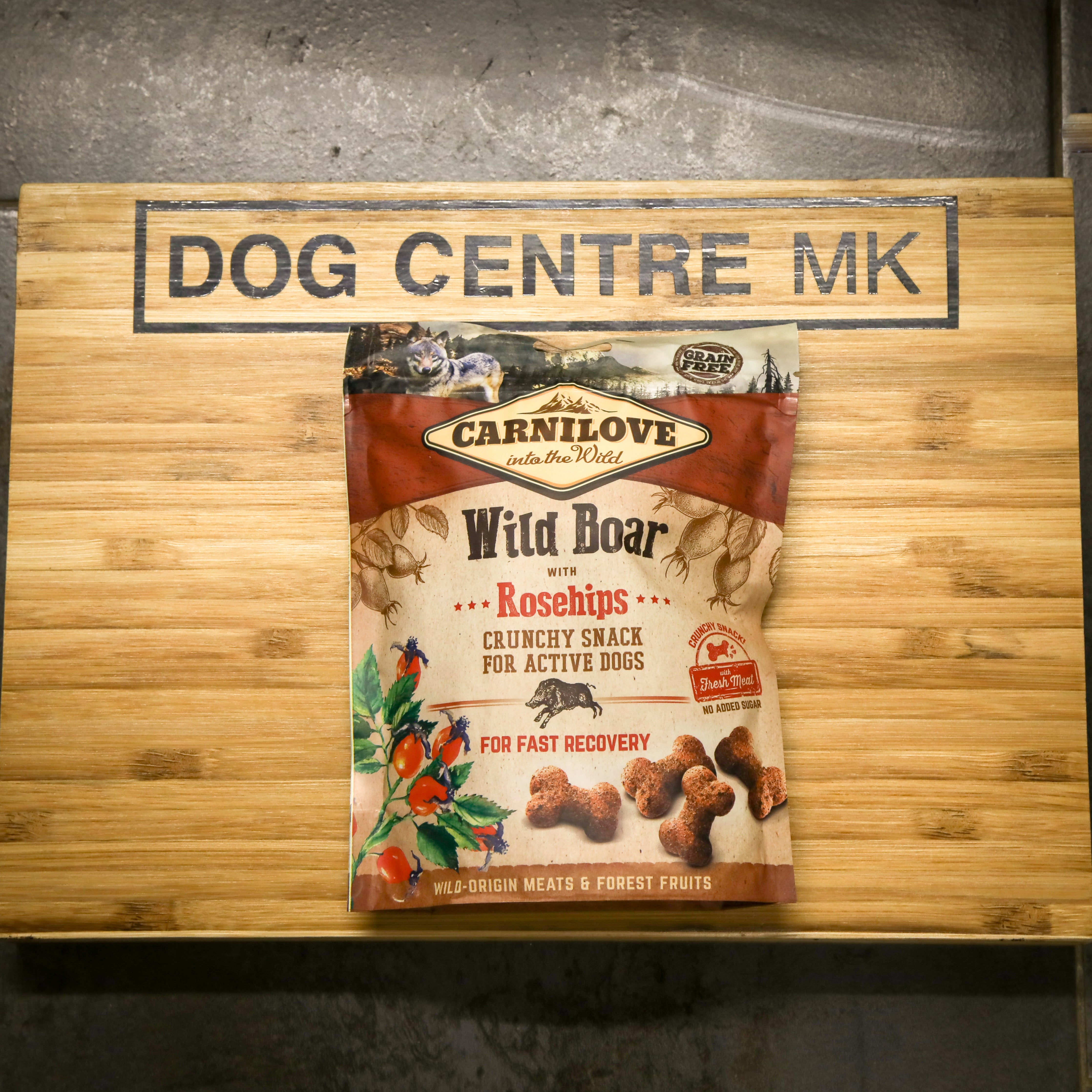 Carnilove Wild Boar with Rosehips snack package on a wooden board with 'Dog Centre MK' sign.