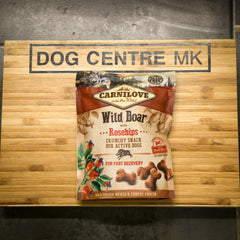 Carnilove Wild Boar with Rosehips snack package on a wooden board with 'Dog Centre MK' sign.