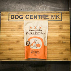 Package of Hackney Dog House Pumpkin Puree Powder on a wooden board with 'Dog Centre MK' branding.