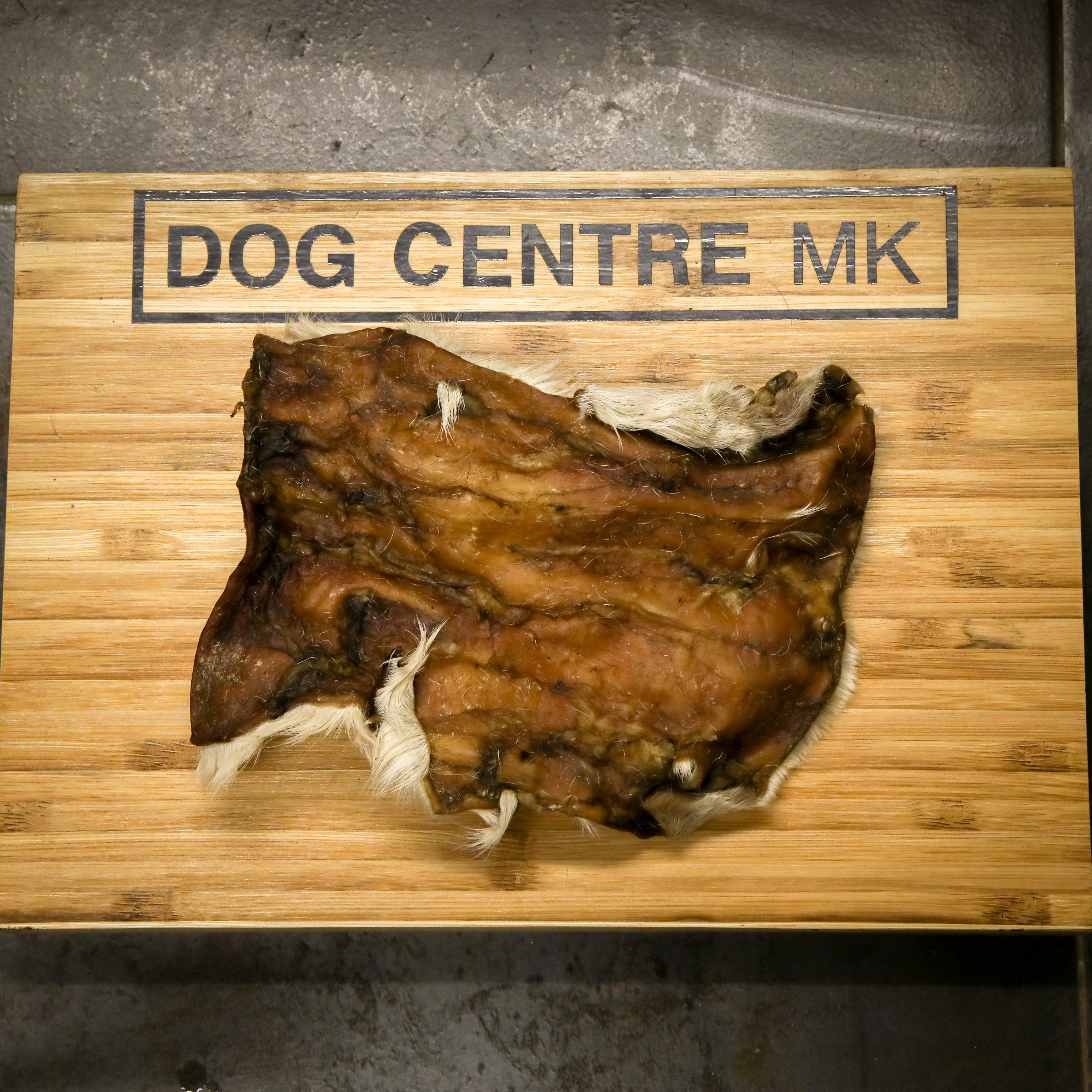 Hairy beef skinskin on a wooden board with 'DOG CENTRE MK' branding.