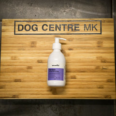 Dog care product bottle on a wooden surface with 'DOG CENTRE MK' sign, seniors hemp oil for pets by infusions