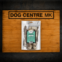 A 150g clear pack of Drool Natural Rabbit Ears with Hair dog treats, displayed on a wooden board branded with the Dog Centre MK logo.