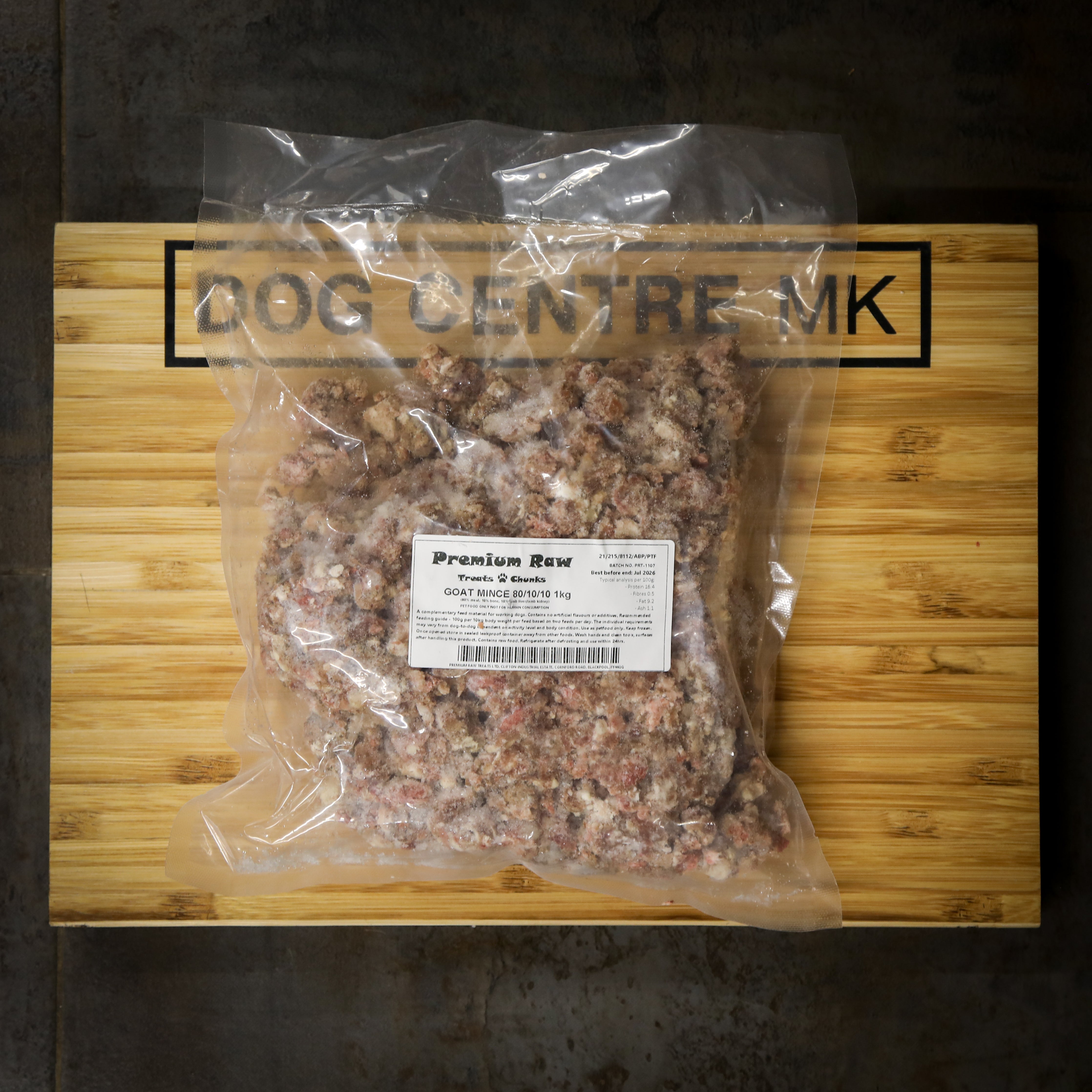 Package of premium raw goat mince on a wooden board with 'Dog Centre MK' branding.